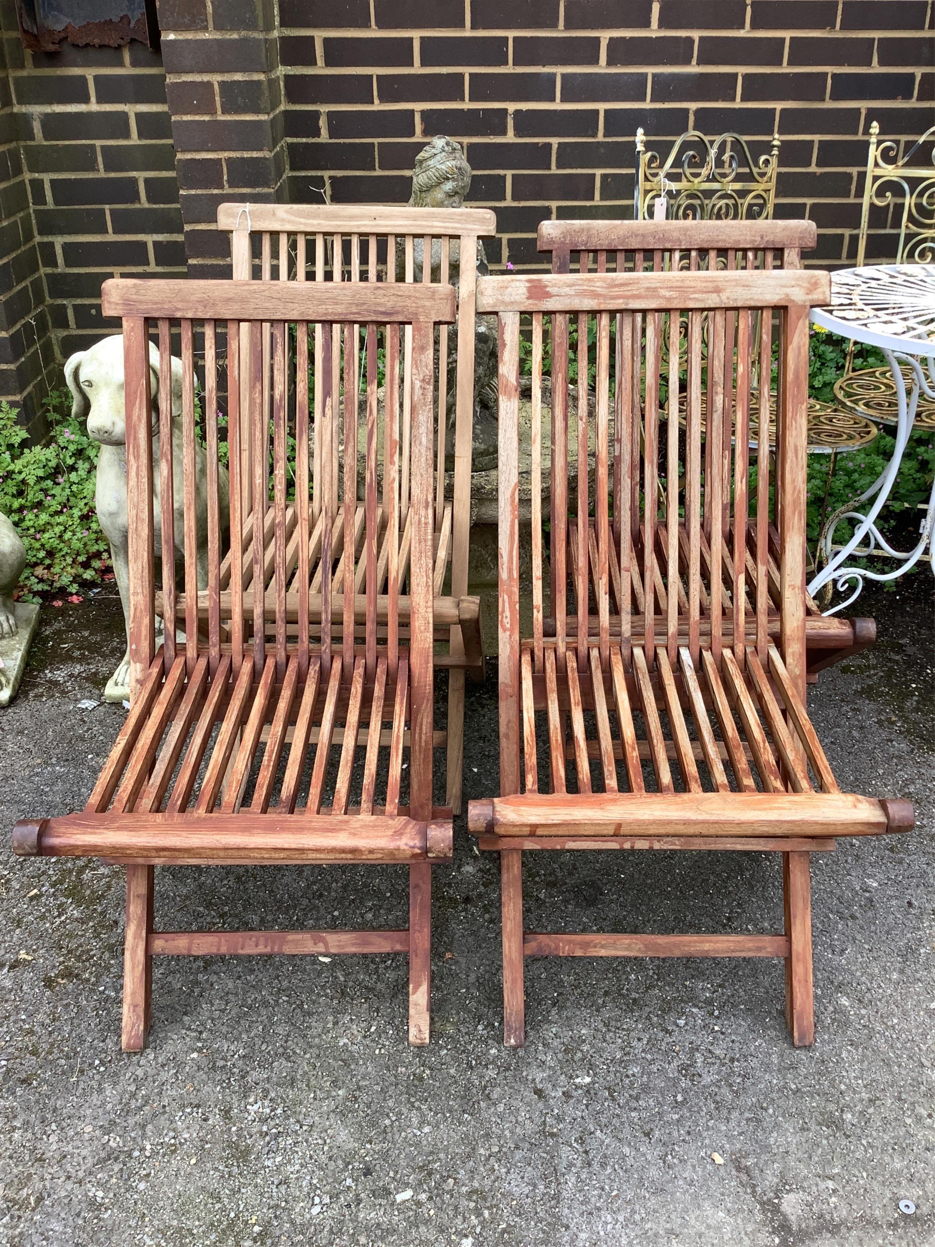 A set of four weathered teak folding garden chairs